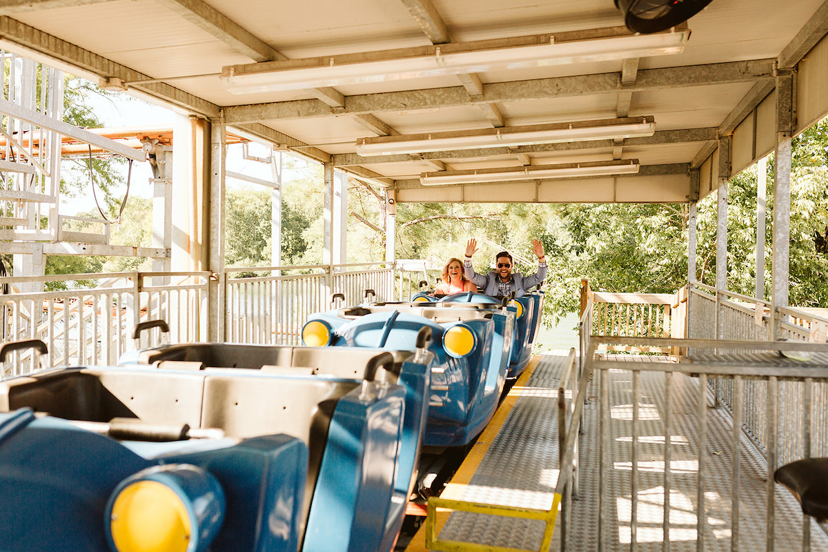 Man and woman with hands raised in the last car of a roller coaster