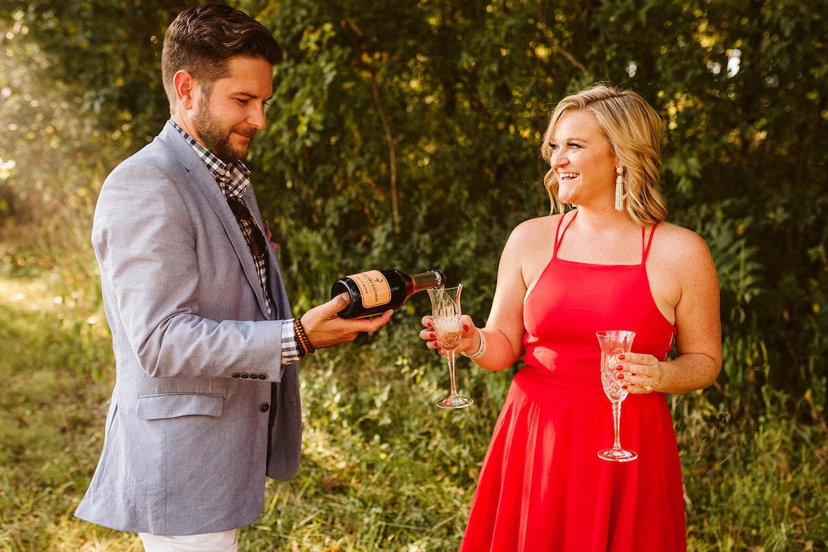 Woman holds crystal glasses while man pours champagne into one