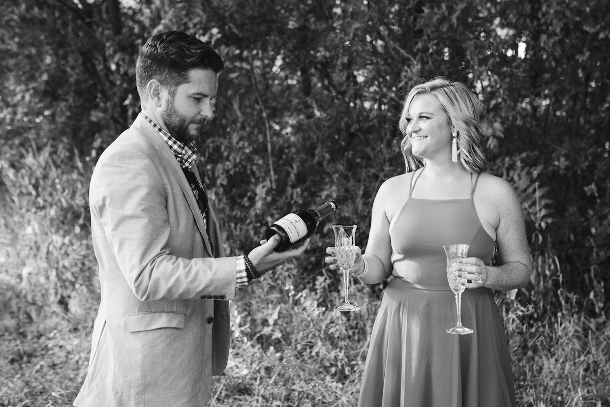 Woman holds crystal glasses while man pours champagne into one