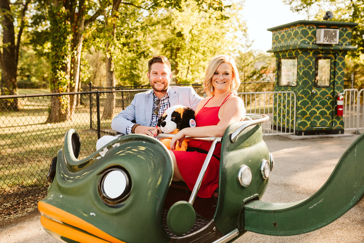 Couple riding in green frog car during their unique engagement photos at Lake Winnie in Chattanooga, TN