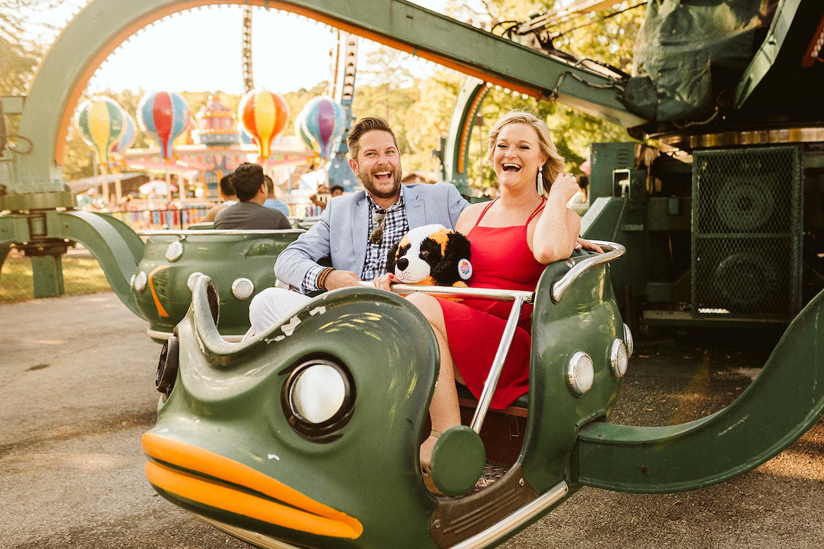 Couple laughs while riding in green frog car during their fun engagement photos at Lake Winnie in Chattanooga, TN