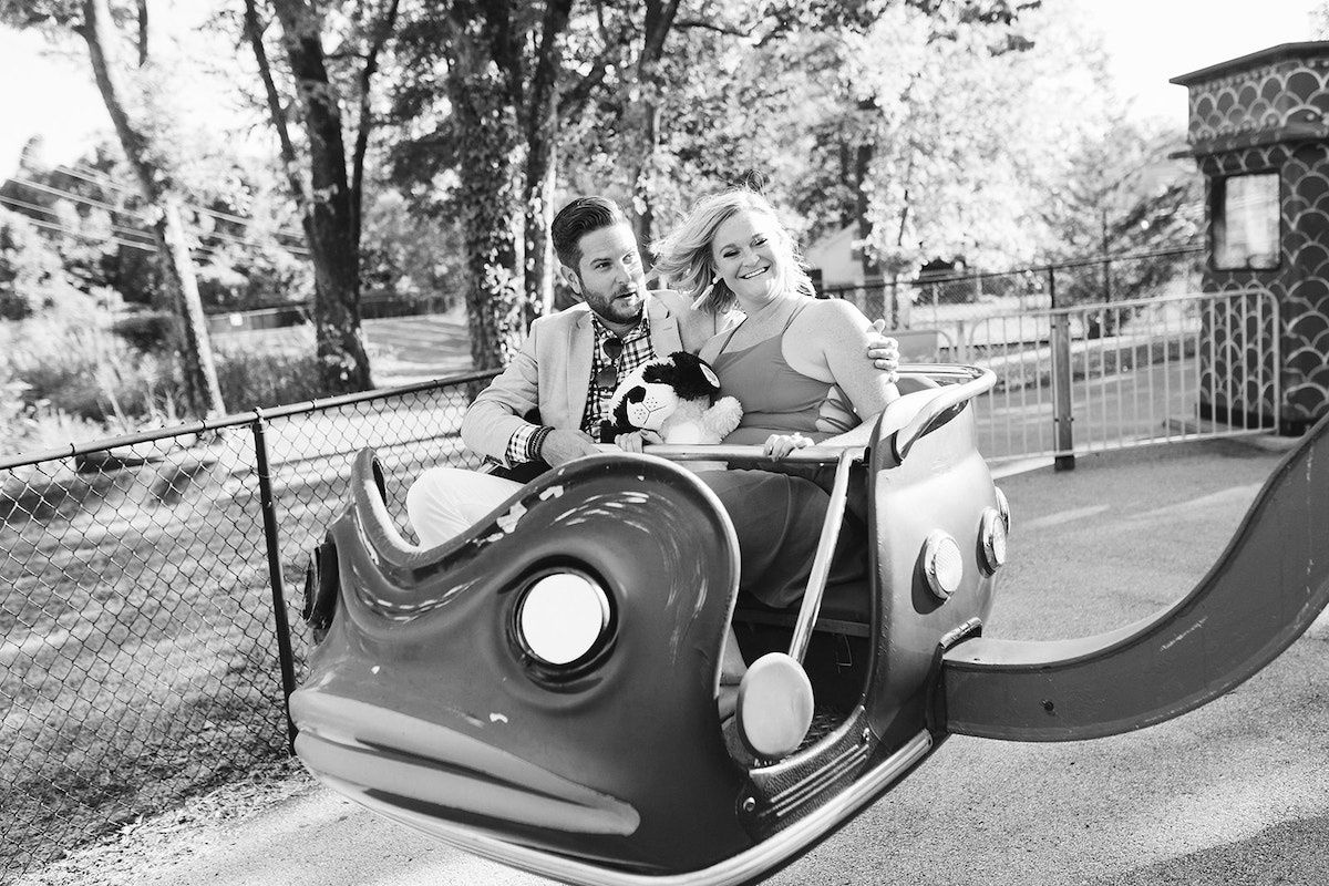 Couple laughs while riding in green frog car during their fun engagement photos at Lake Winnie in Chattanooga, TN