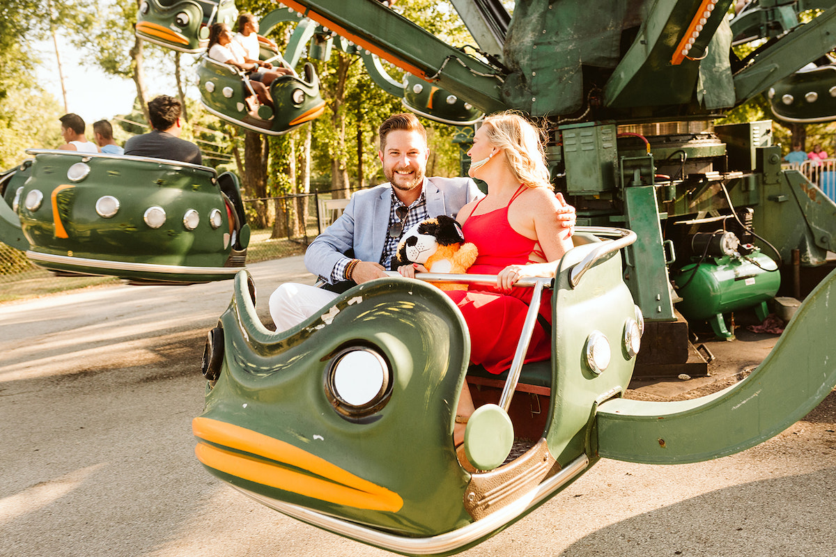 Man and woman smile at each other on a green frog carnival ride