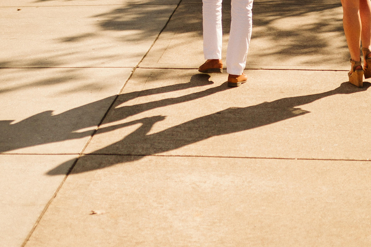 Shadow of man and woman holding hands and walking on a sidewalk