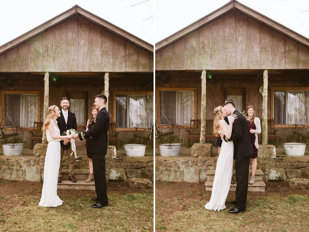 Bride and groom share their first kiss in front of antique family cabin porch during their small intimate wedding