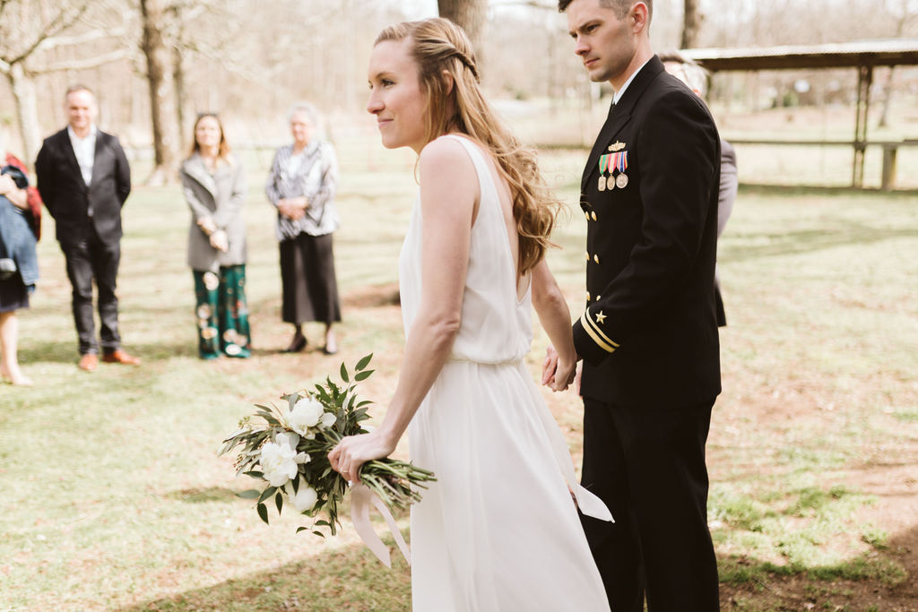 Bride and groom holding hands face their family members