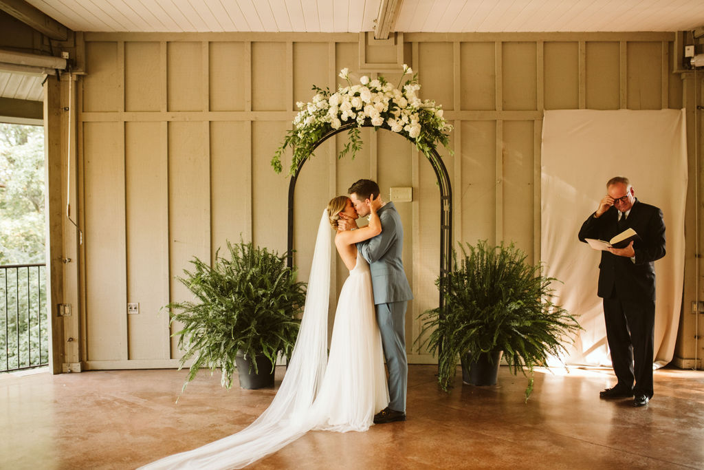 Bride and groom kiss under simple floral archway during open-air Lookout Mountain wedding ceremony in Chattanooga, Tennessee