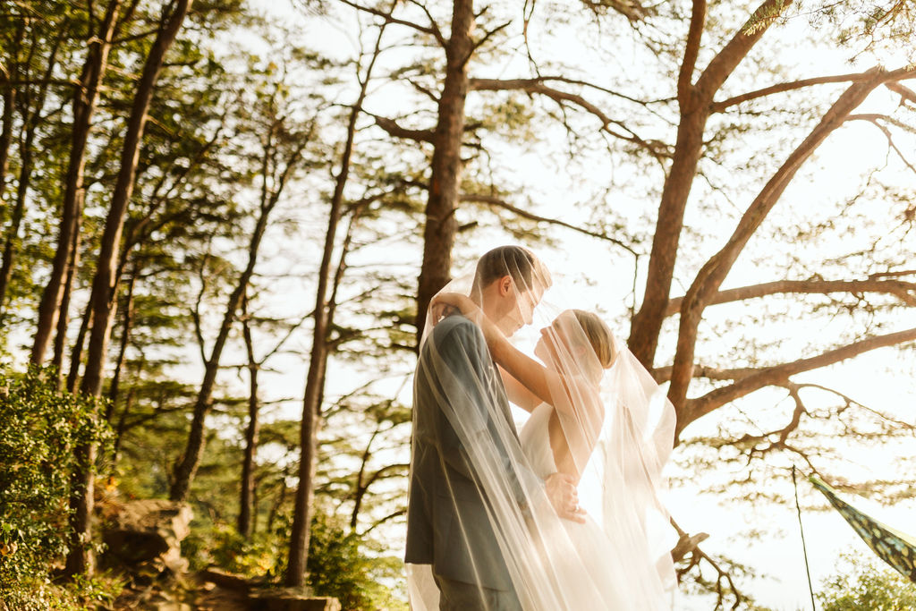 Bride and groom hug under her veil in the woods at bride and groom portrait session on Sunset Rock in Chattanooga, Tennessee