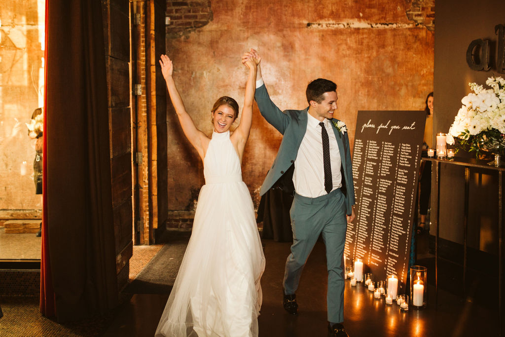 Bride and groom walk into downtown Chattanooga candlelit reception with arms raised