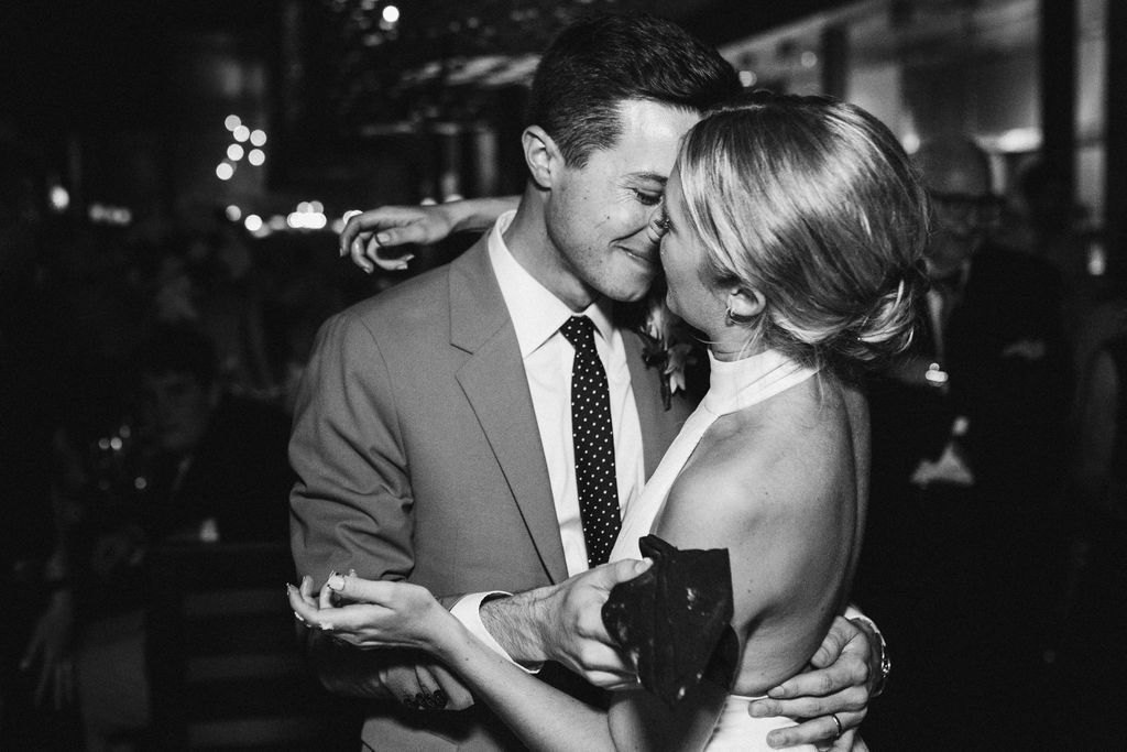 Bride and groom lean in for a kiss. Her hands covered in cake crumbs and he holds a napkin.