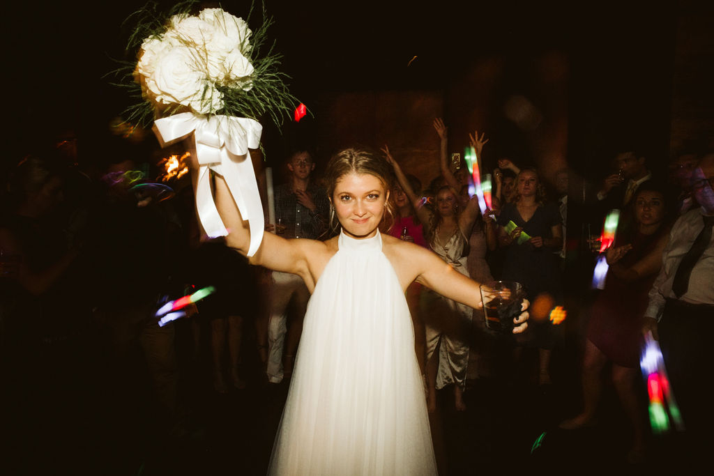 Bride holds bouquet above her shoulder, getting ready to toss it to wedding guests