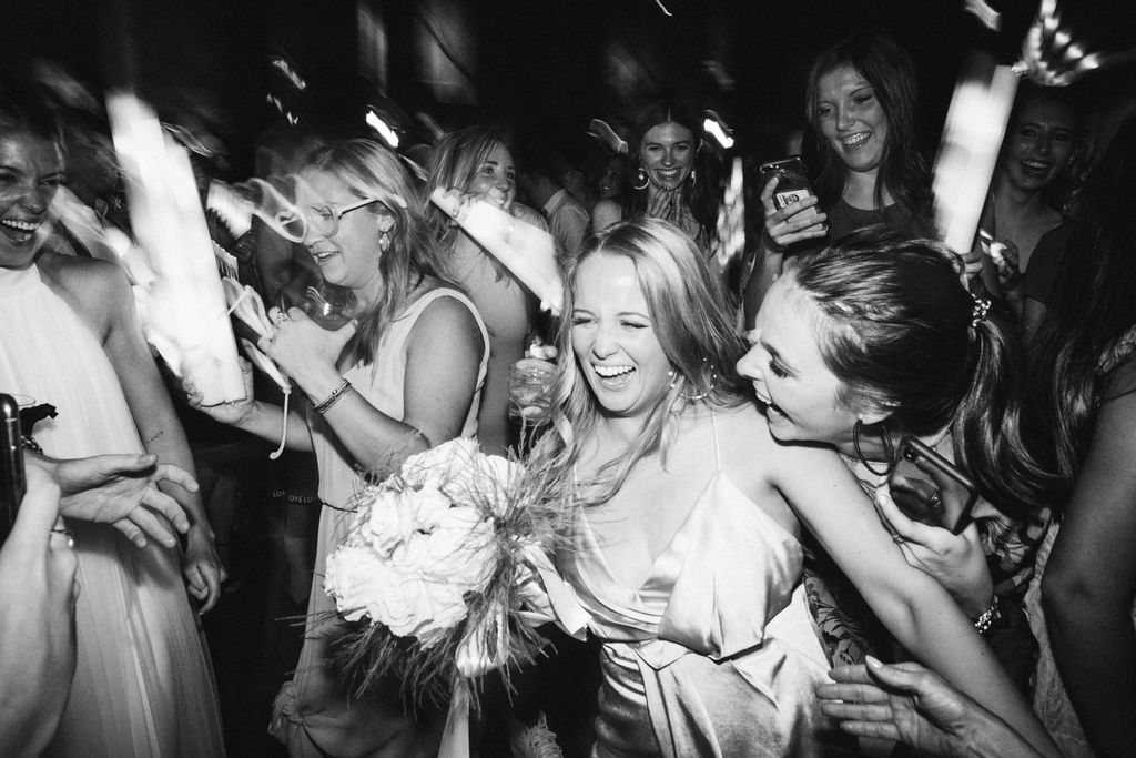 Wedding guests laugh as one woman catches the bride's bouquet