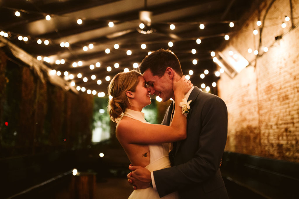 bride and groom hug and touch foreheads under strands of backyard lights at downtown Chattanooga, Tennessee wedding reception