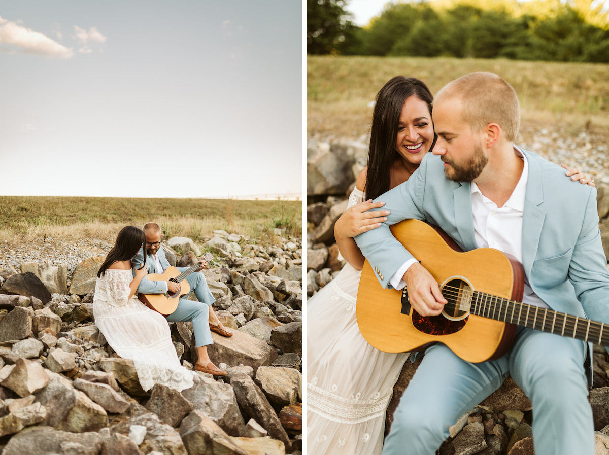 Man in light blue suit and woman in strapless white dress sit on large rocks. He plays a guitar while she smiles.