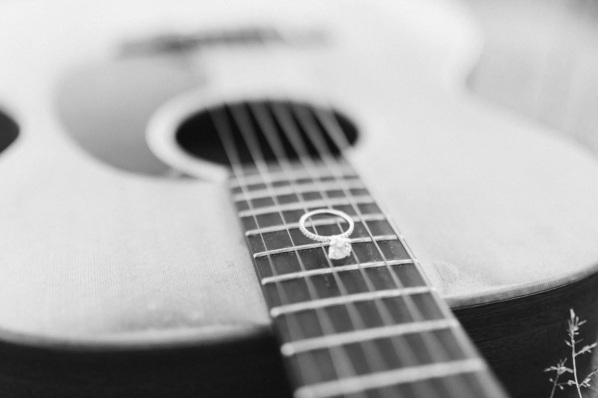 Diamond engagement ring sits on guitar frets