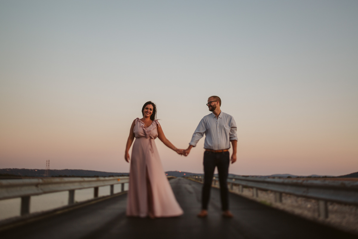 Man and woman stand hand-in-hand on Raccoon Mountain's loop drive at golden hour.