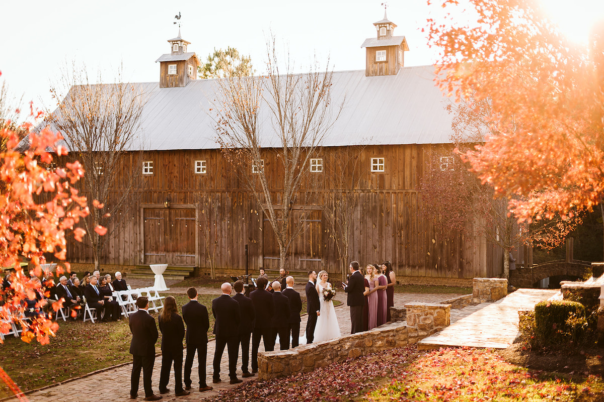 Bridal party stands on antique brick carriage path in front of hand-pegged Amish barn at The Homestead at Cloudland Station