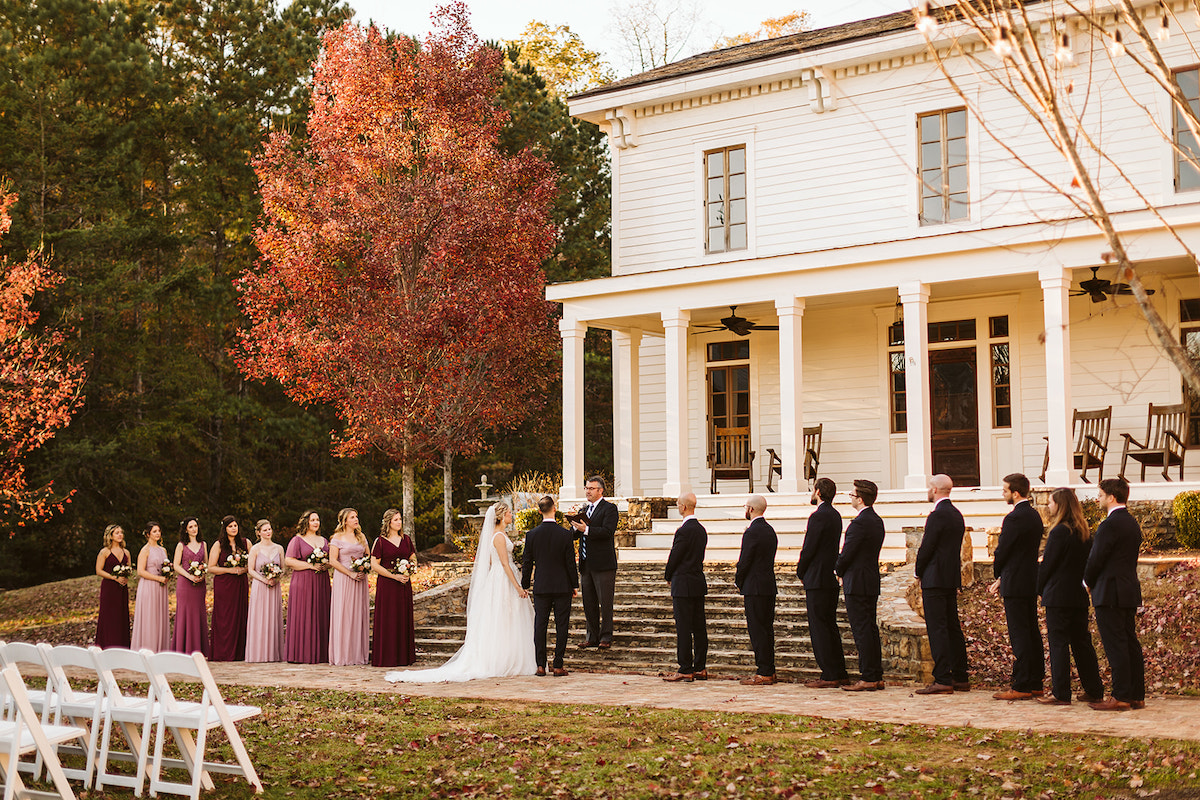 Bridal party stands on antique brick carriage path in front of white farmhouse at The Homestead at Cloudland Station