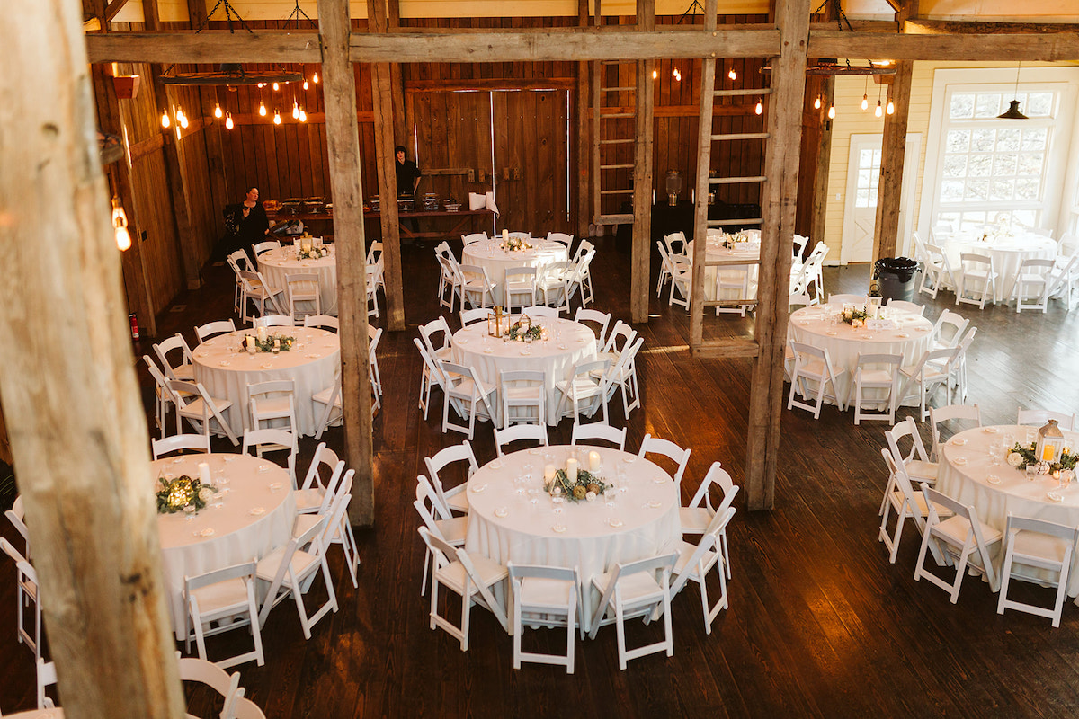 The Homestead at Cloudland Station with open high, barn rafters and wooden support beams. White table linens on round tables.