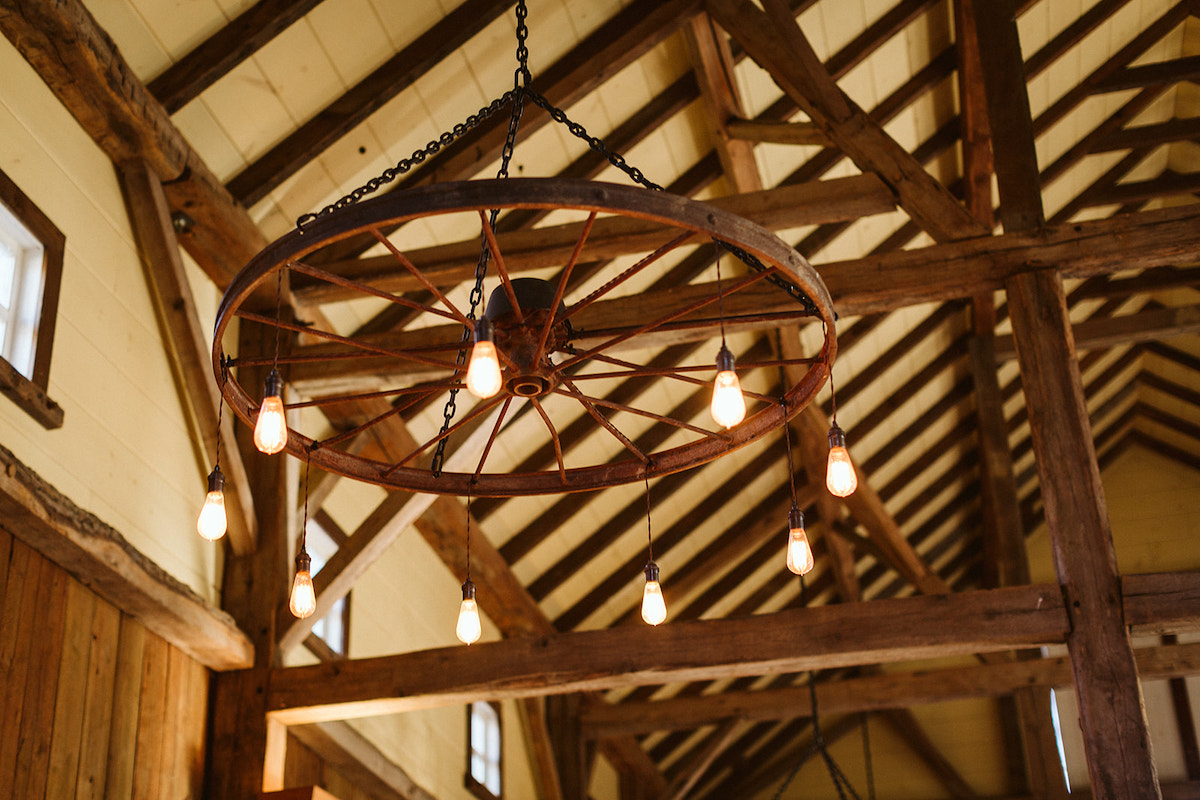 Wagon wheel light fixture suspended by black chain under the exposed wooden rafters at The Homestead at Cloudland Station