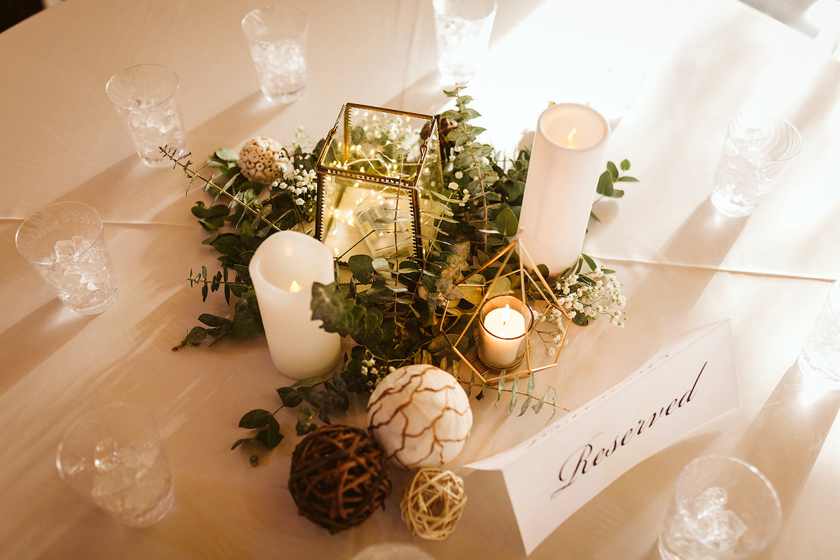Simple table decorations of greens and candles next to "Reserved" sign