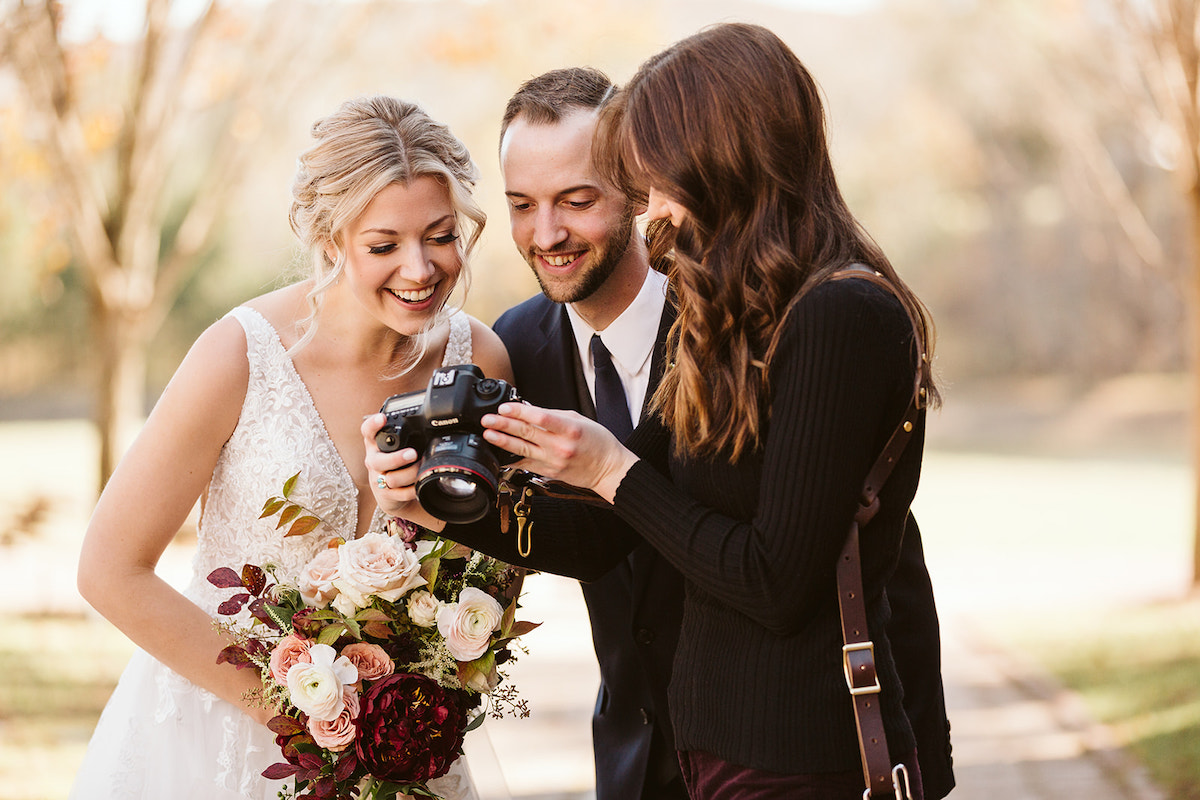 Bride and groom overlook their Chattanooga wedding photographer's camera screen, previewing a photo