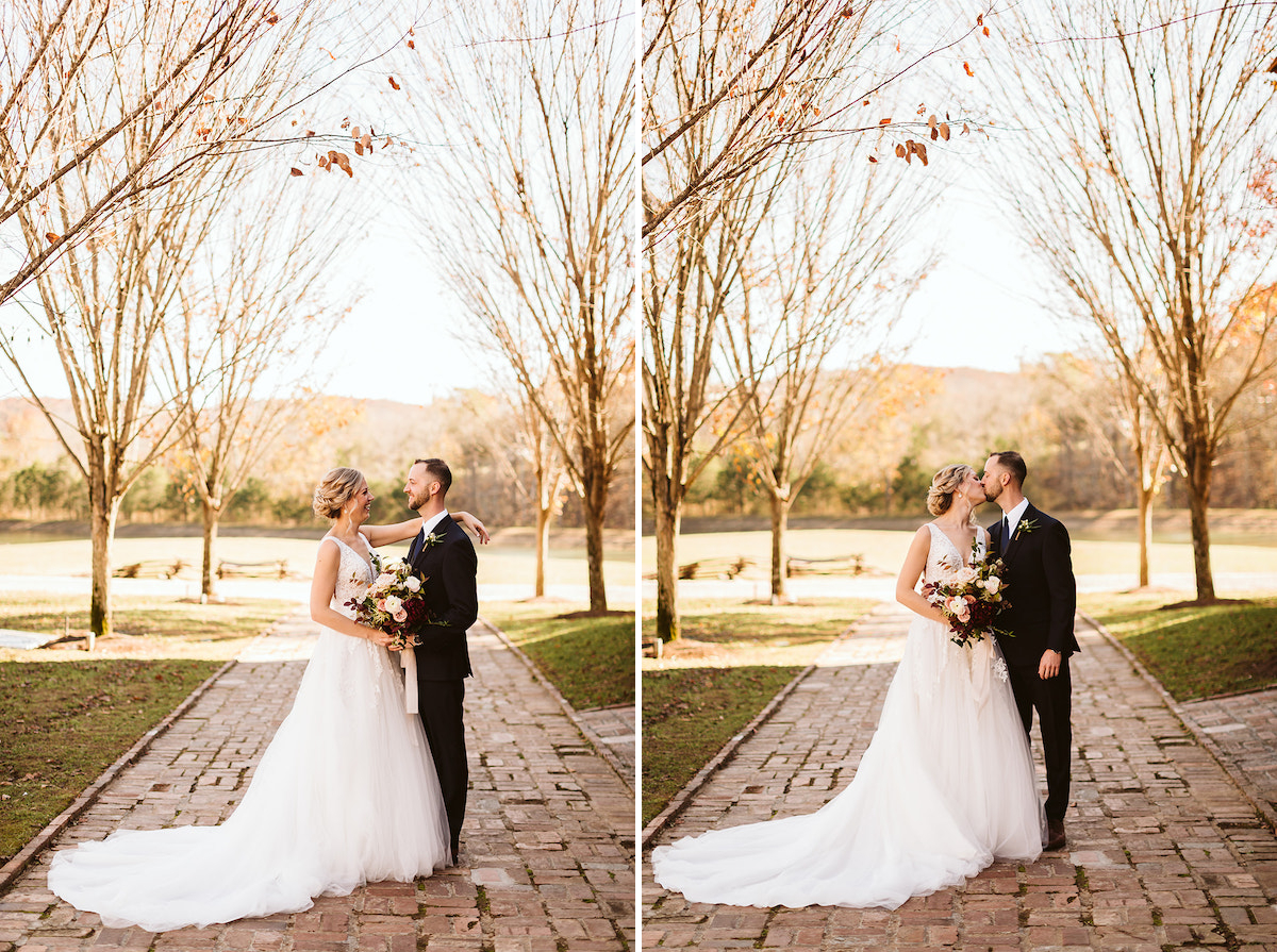 Bride and groom kiss on antique brick carriage path between trees