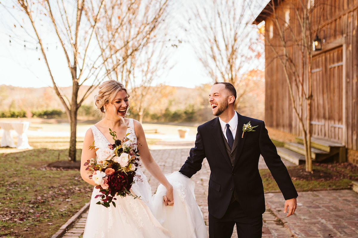 Bride and groom laugh as they walk down antique brick carriage path