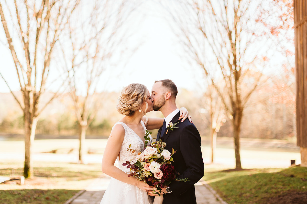 Bride and groom kiss, her hand around his shoulder