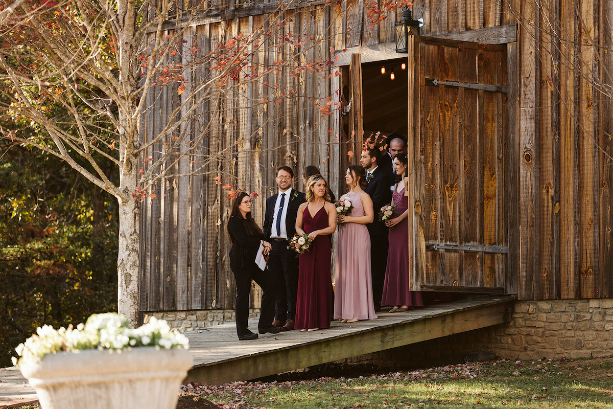 Wedding party lines up between tall wooden barn doors