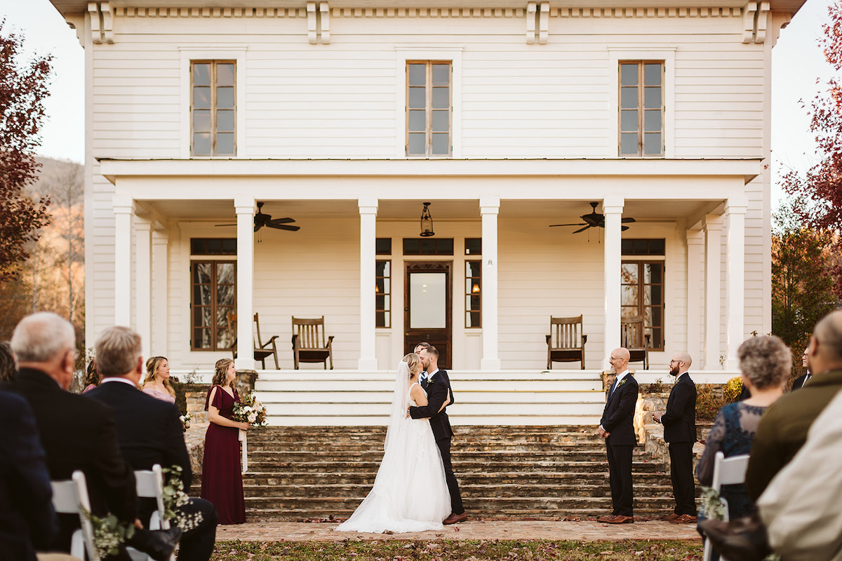 Bride and groom kiss at the base of the stone steps in front of Peacock Hall