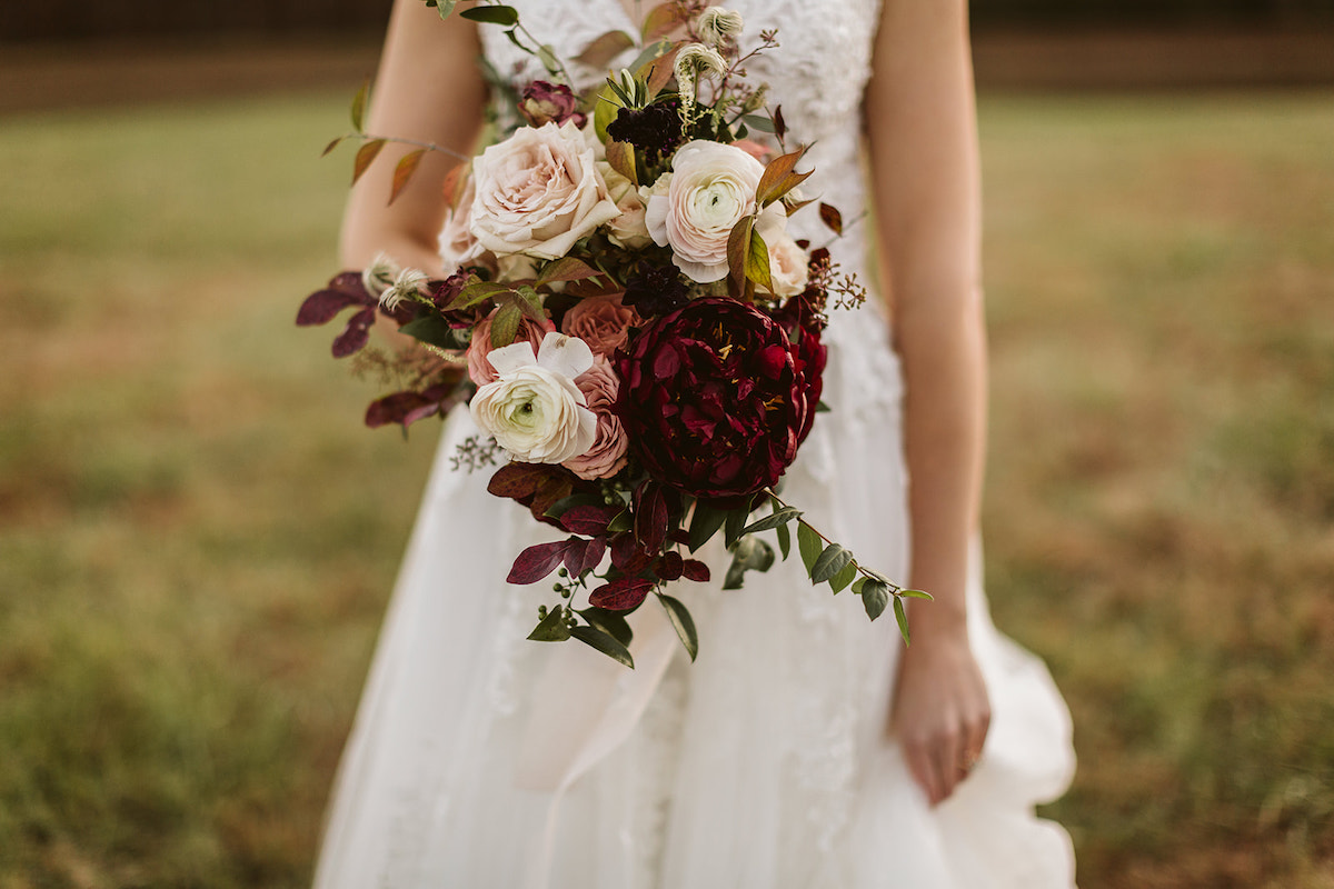 Bridal bouquet by Petaline contains deep red flowers, pink and white roses, and greenery.