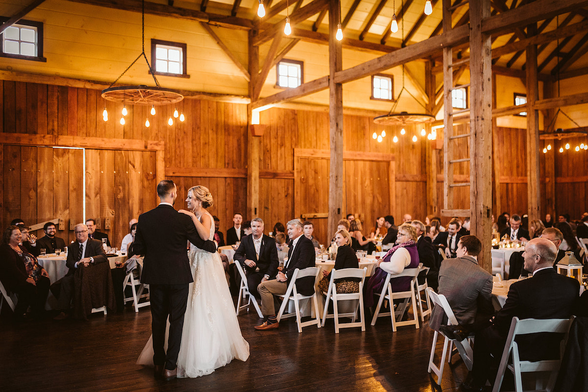 Bride and groom dance under the exposed beam ceiling of The Homestead at Cloudland Station while guests watch from tables.