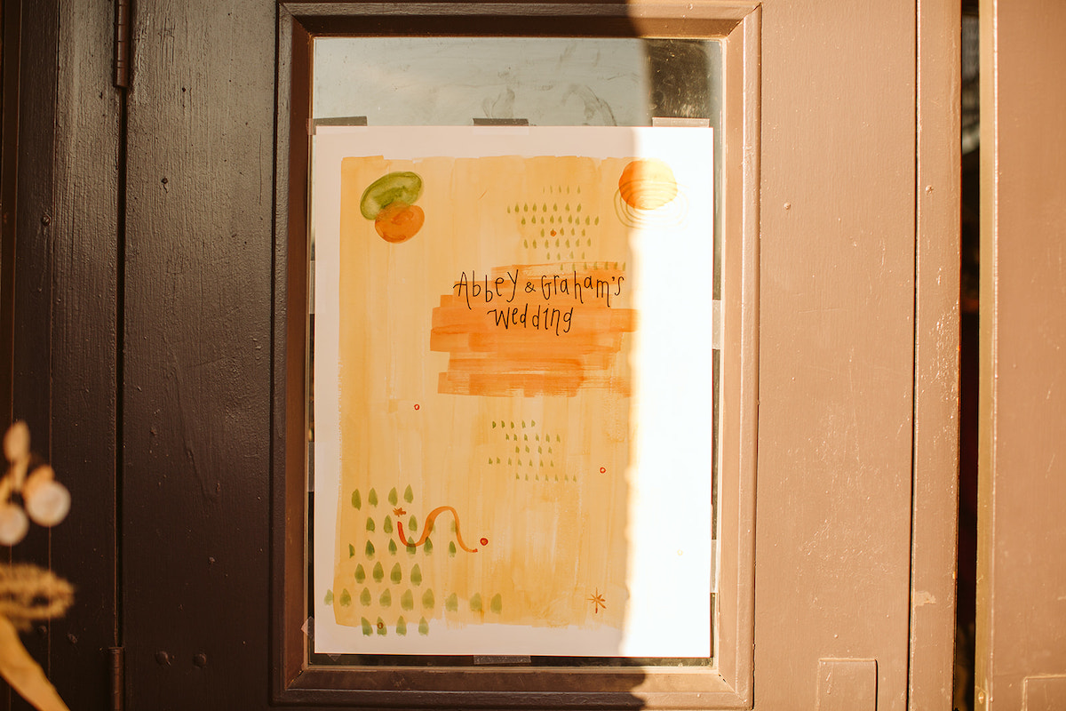 Sign posted in the window of a brown door announcing Abbey and Graham's wedding