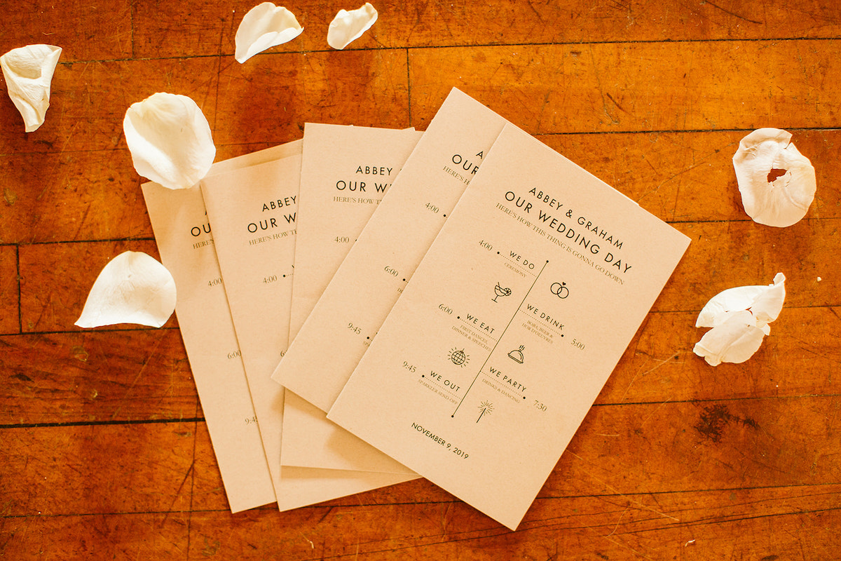 flat lay of Abbey and Graham's wedding day programs surrounded by white flower petals