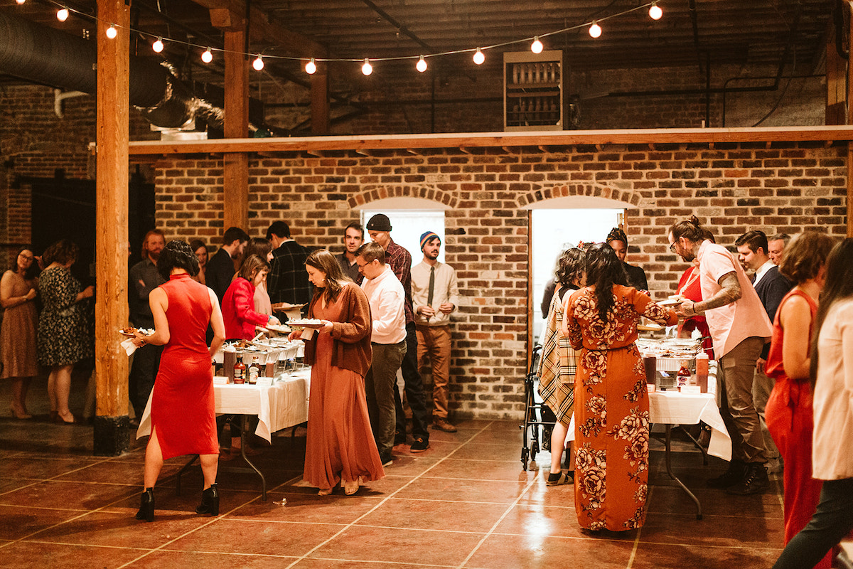 People serving themselves from buffet in front of an exposed brick wall at The Old Woolen Mill