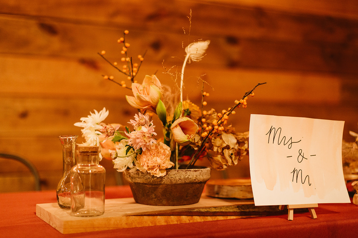 Southerly Flower Farm reception table centerpiece with low terra cotta planter and wild flowers next to "Mrs & Mr" sign