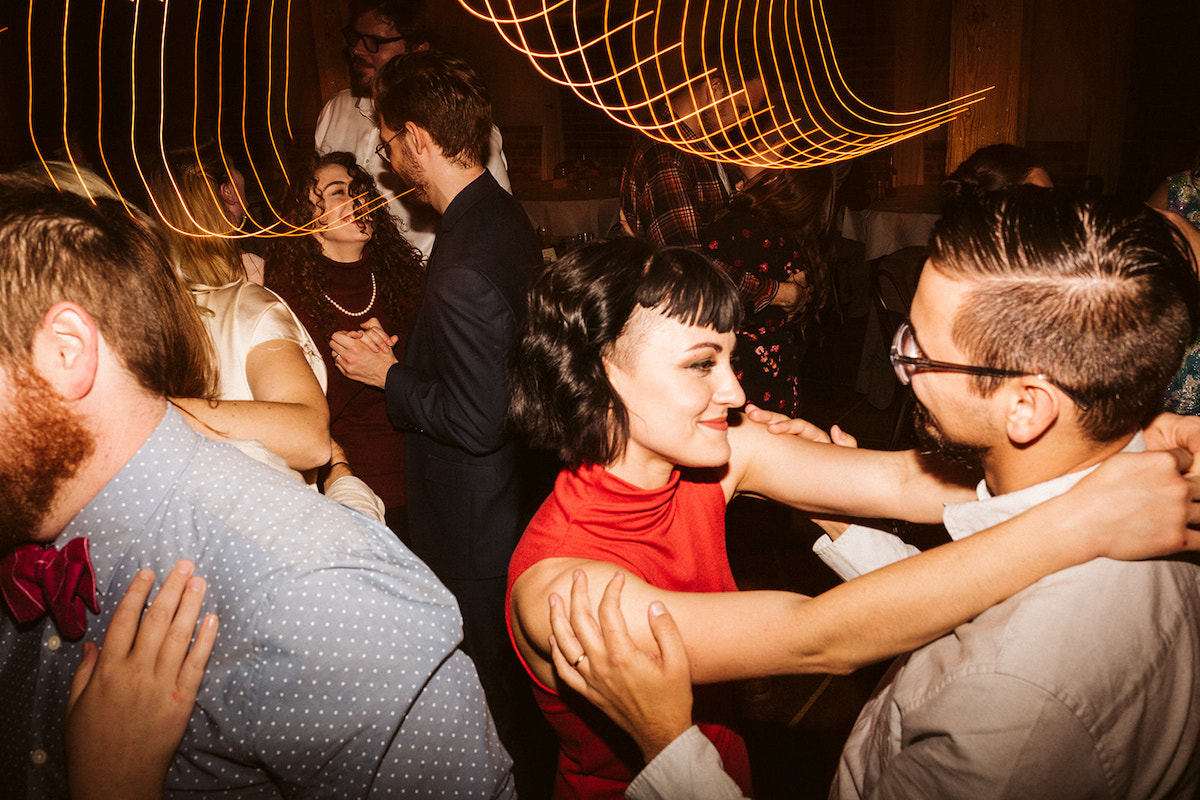 Woman in red dress dances with her hands around a man's neck