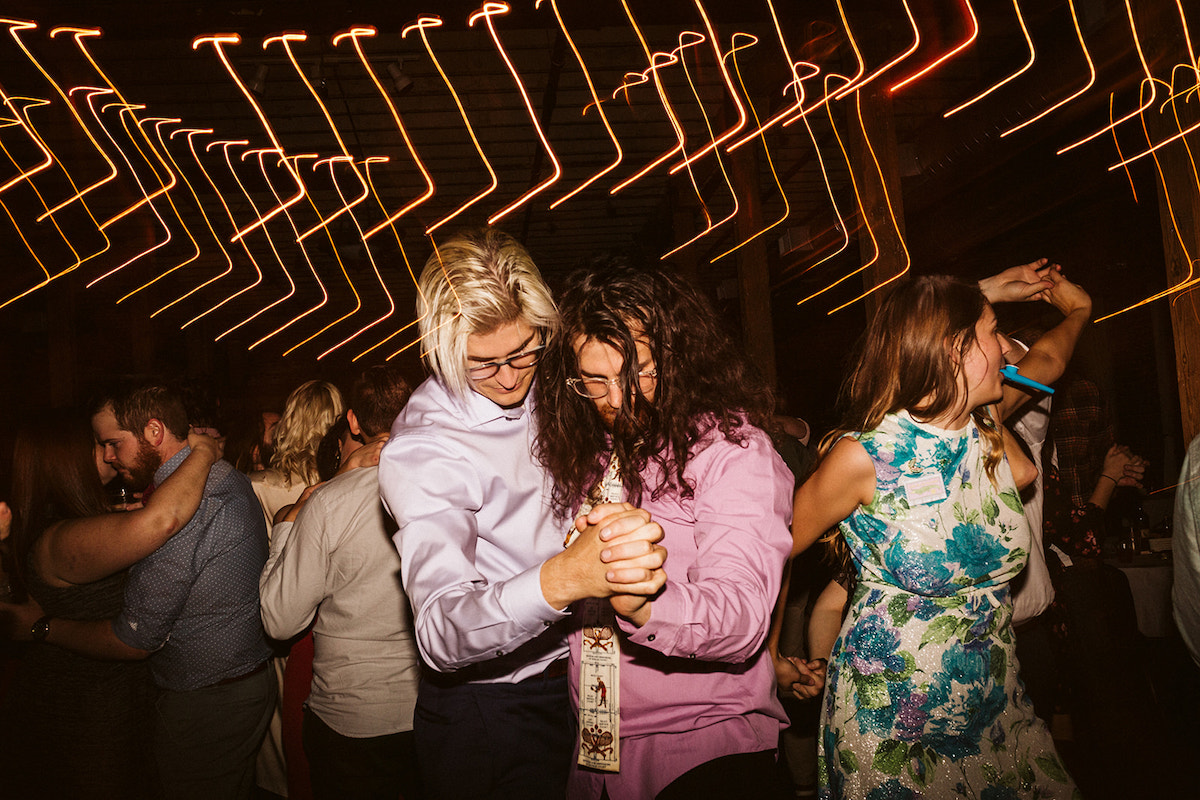 Two men in purple shirts hold hands and dance