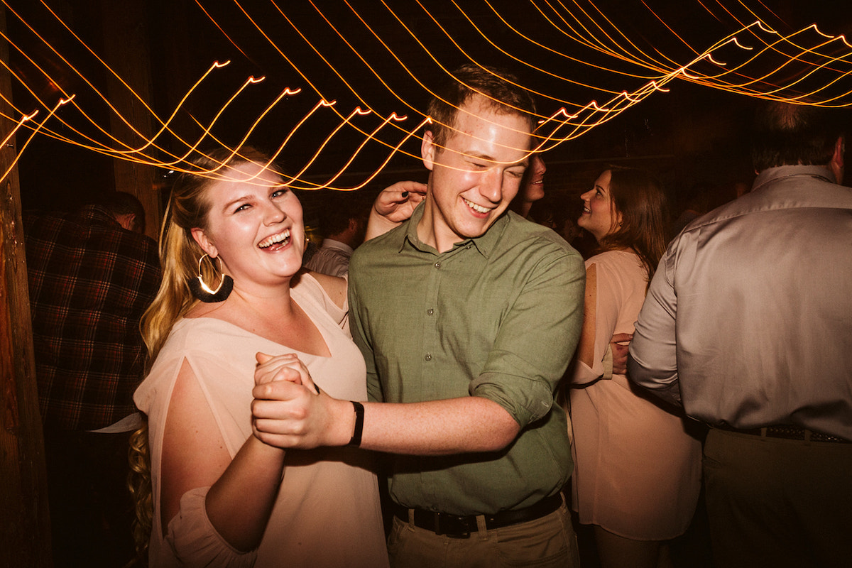 Man and woman dance under lights during wedding reception at Weaver's Room in The Old Woolen Mill in Cleveland, Tennessee