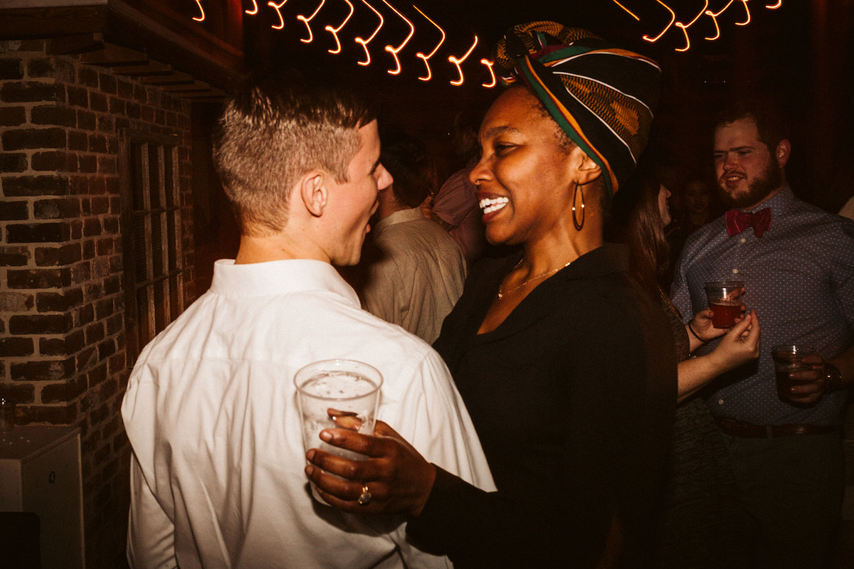 Man and woman dance under lights during wedding reception