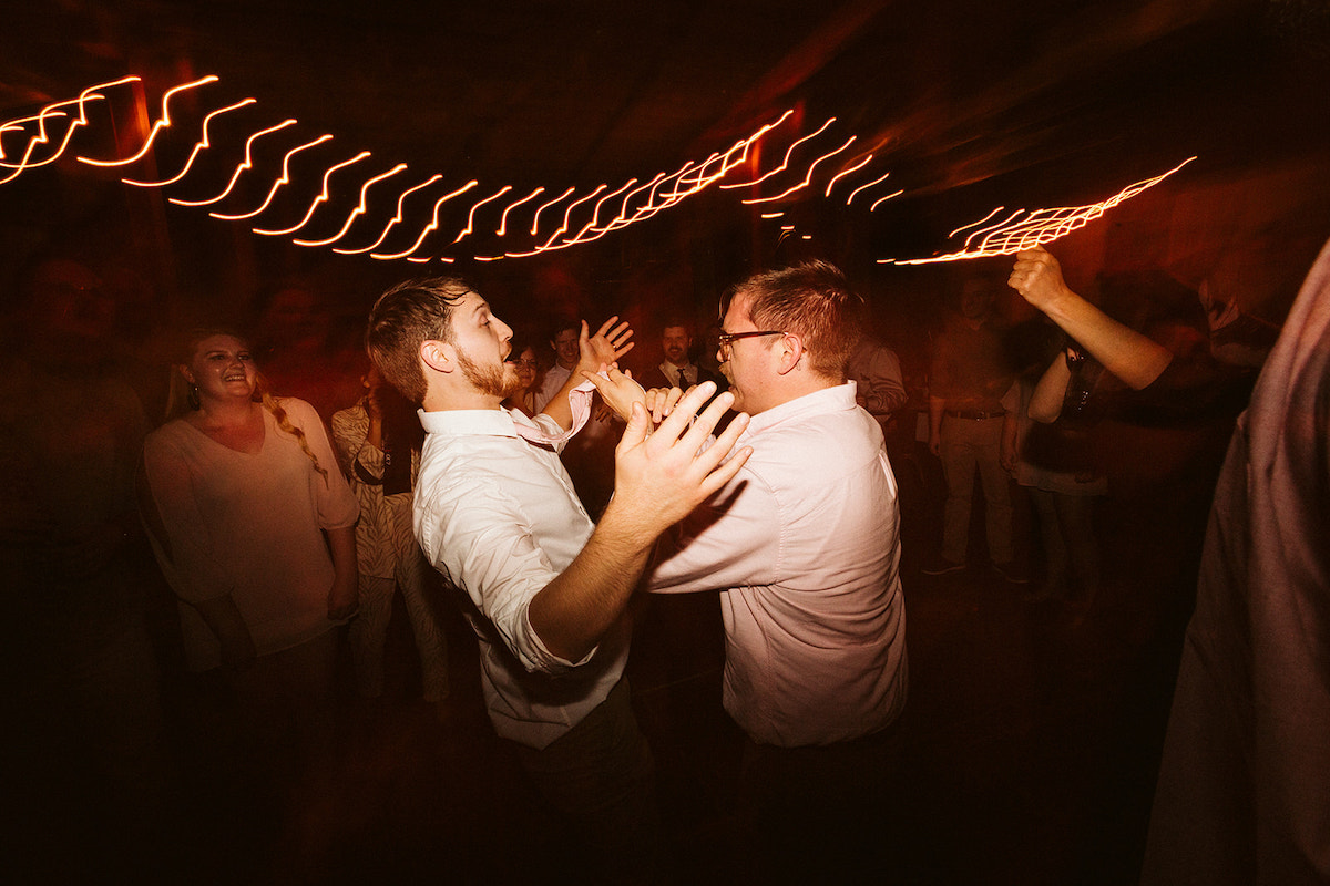 Groom and friend dance encircled by friends