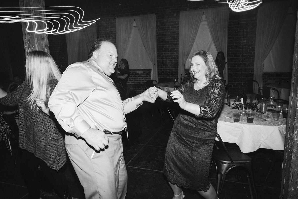 Man and woman dance next to round dining table