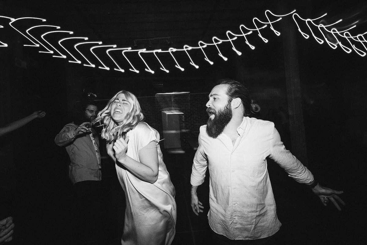 Man and woman sing and dance under lights at a wedding reception