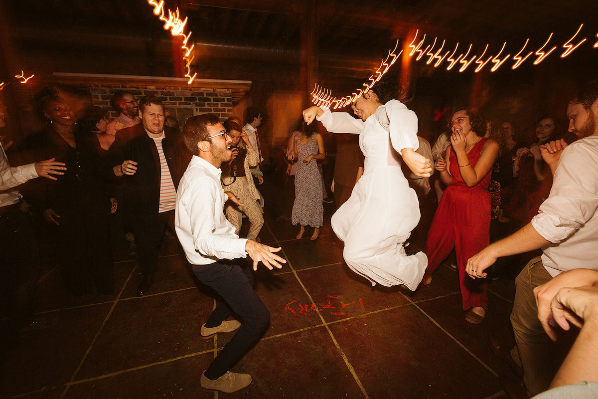 Bride leaps into the air while dancing with friends