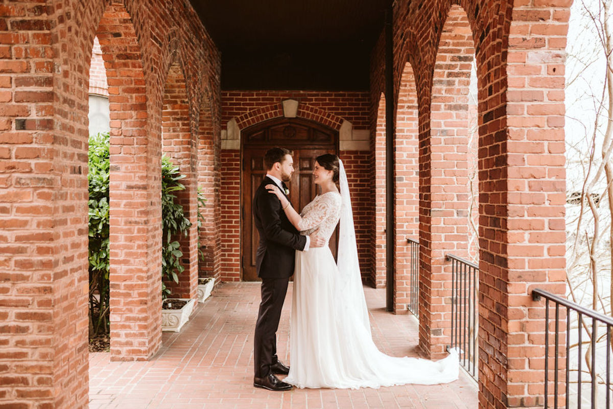 Bride and groom share first look under covered walkway between brick archways