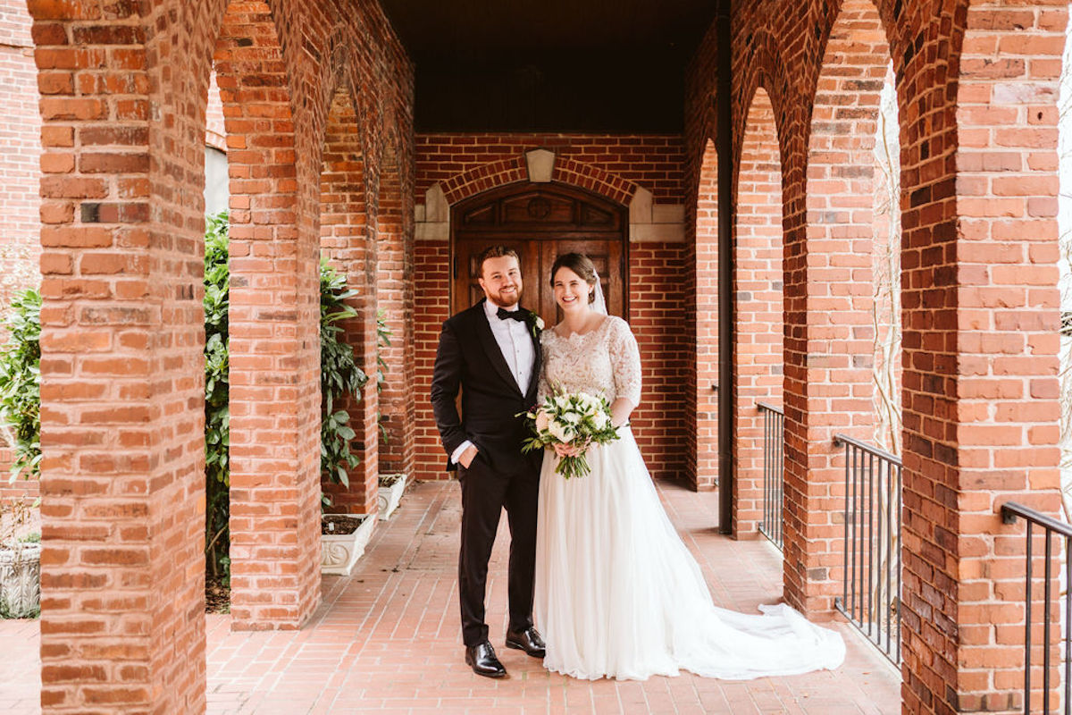 Bride and groom under covered walkway between brick archways