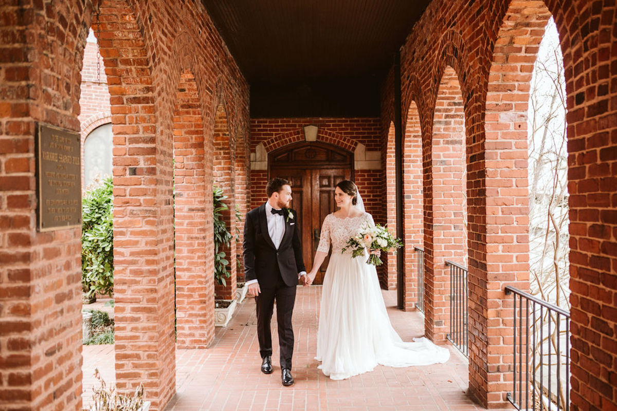 Bride and groom under covered walkway between brick archways