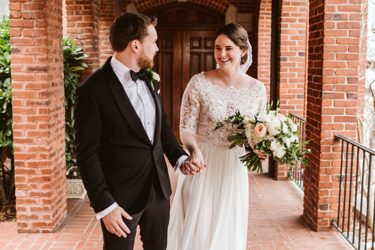 Bride and groom under covered walkway between brick archways