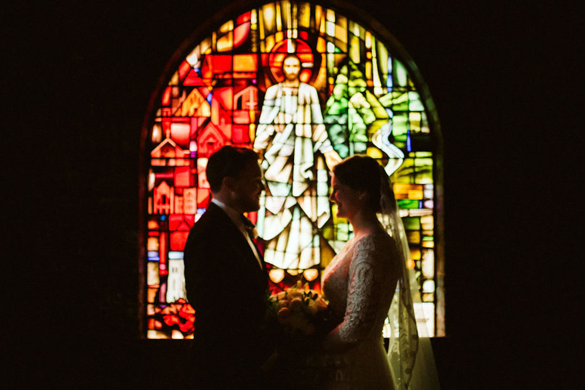 Bride and groom silhouette against stained glass window